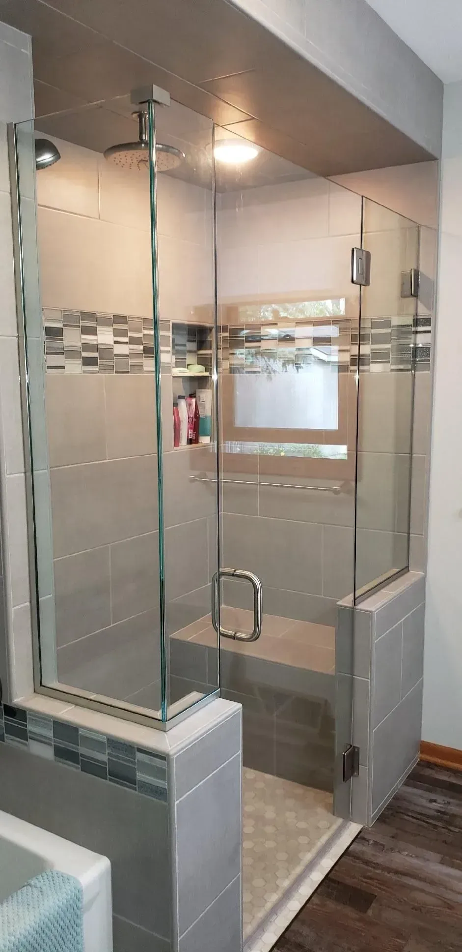 A bathroom with a walk in shower with a glass door.