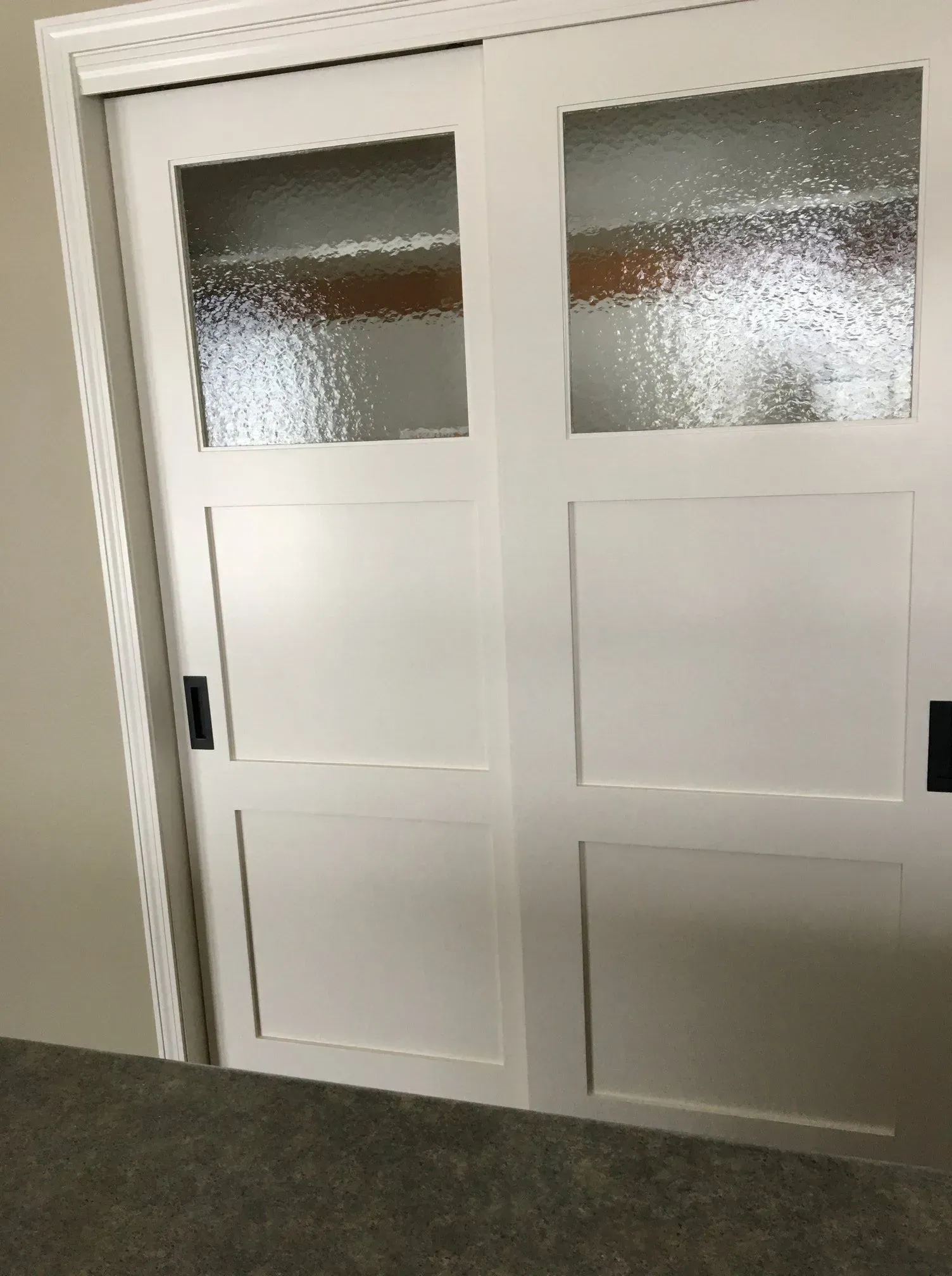 A pair of white sliding doors with clear glass in a room.