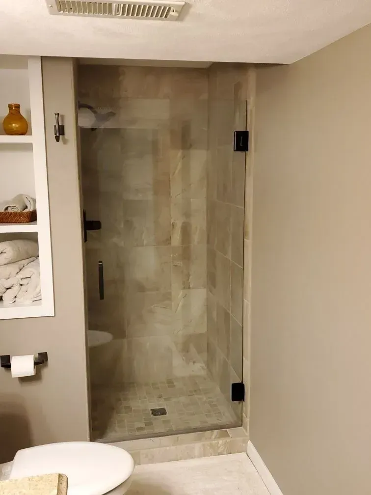 A bathroom with a toilet and a shower with a glass door.