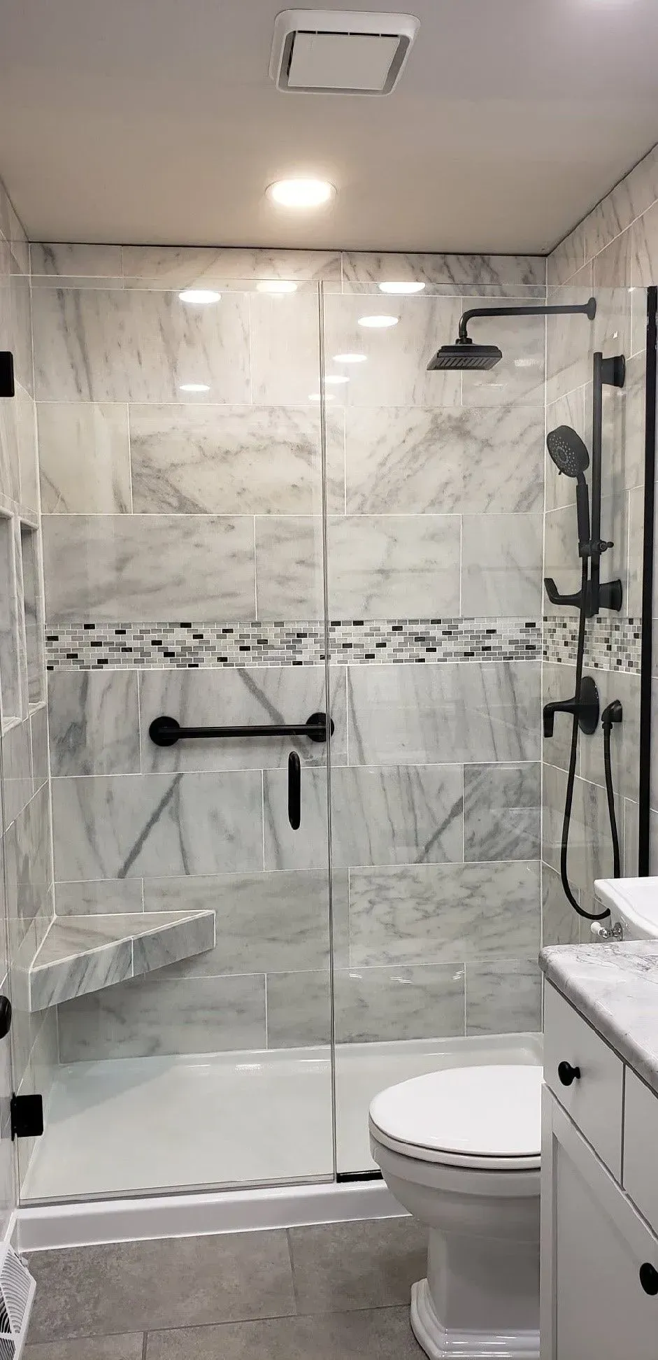 A bathroom with a walk in shower , toilet and sink.