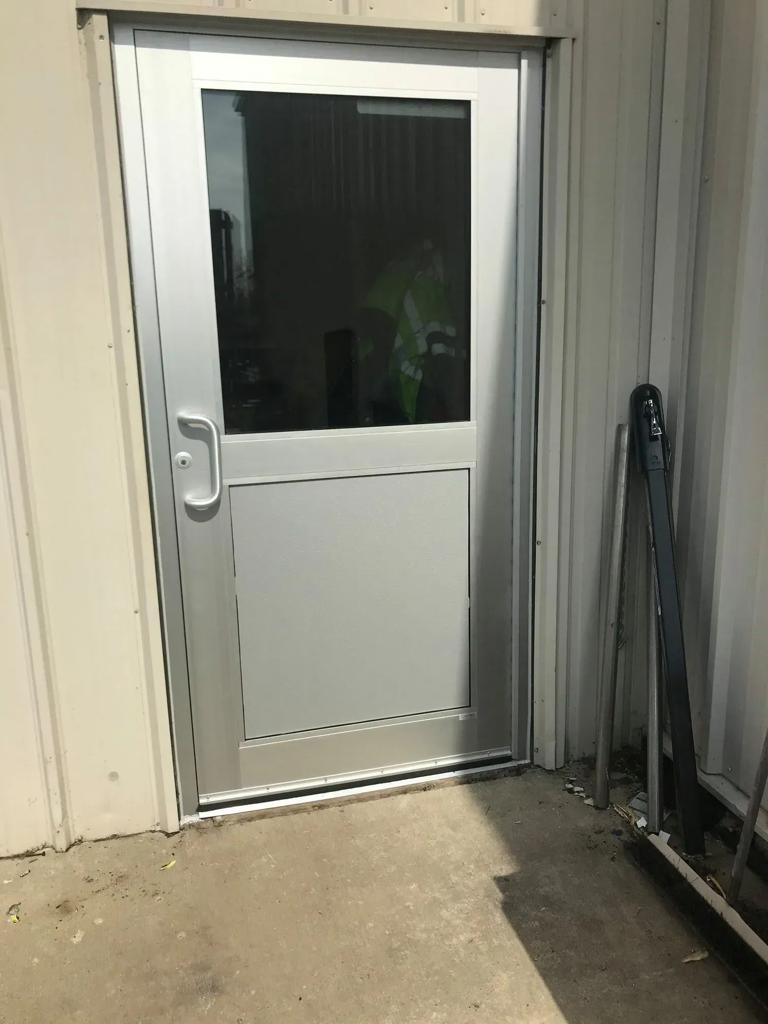 A door with a glass window is sitting on the side of a building.