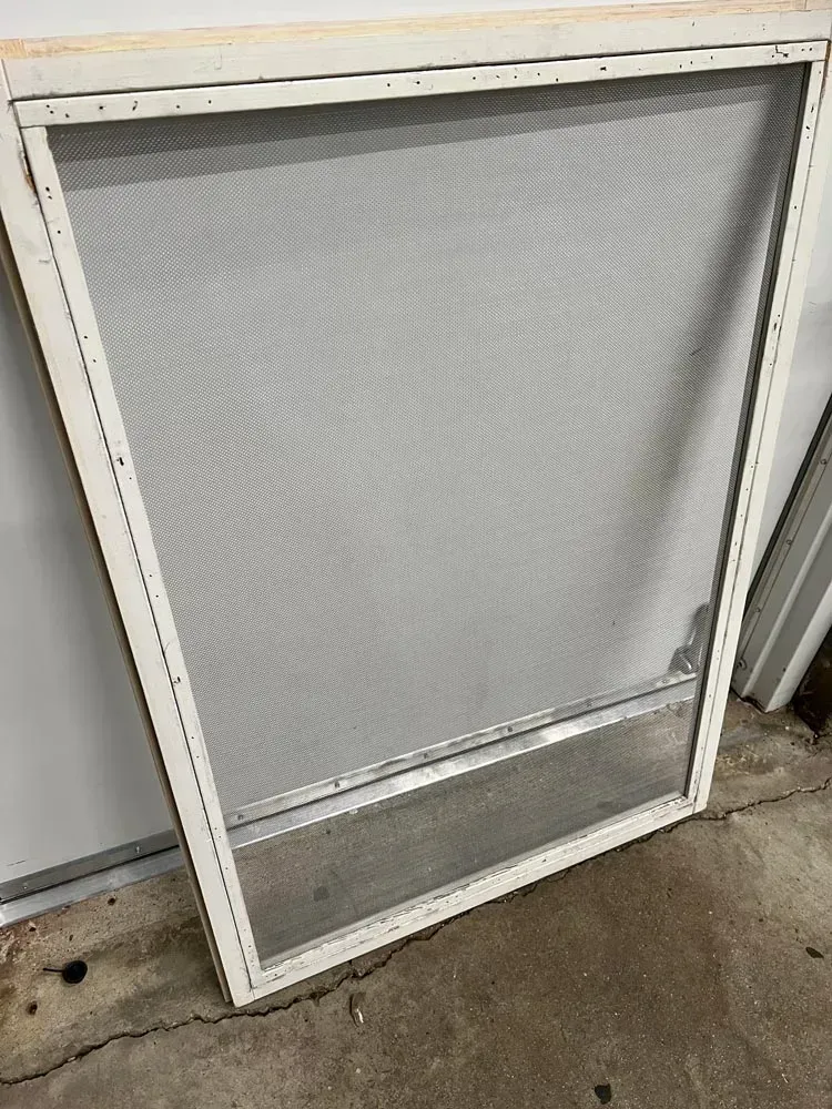 A white mosquito screen is sitting on a concrete floor.