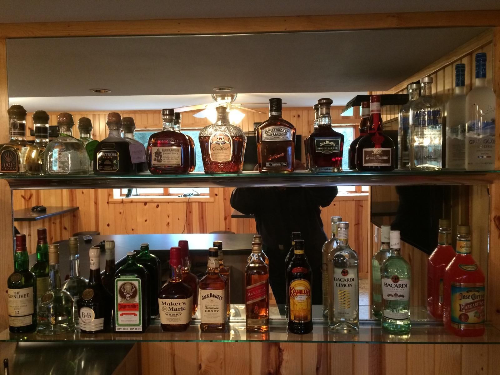 Bottles of liquor are lined up on a glass shelf
