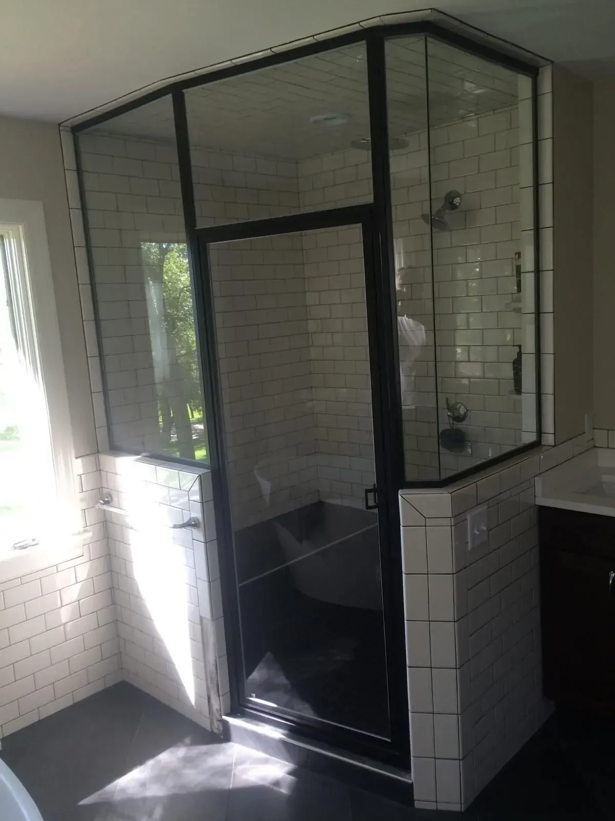 A bathroom with white tiles and a glass shower door