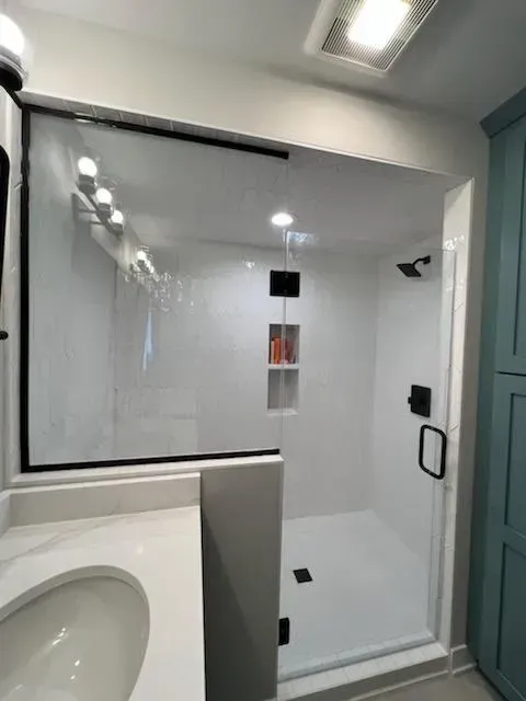 A bathroom with a walk in shower and a sink.