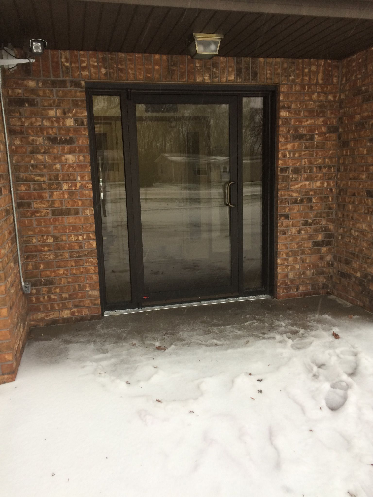 A brick building with a glass door and snow on the ground