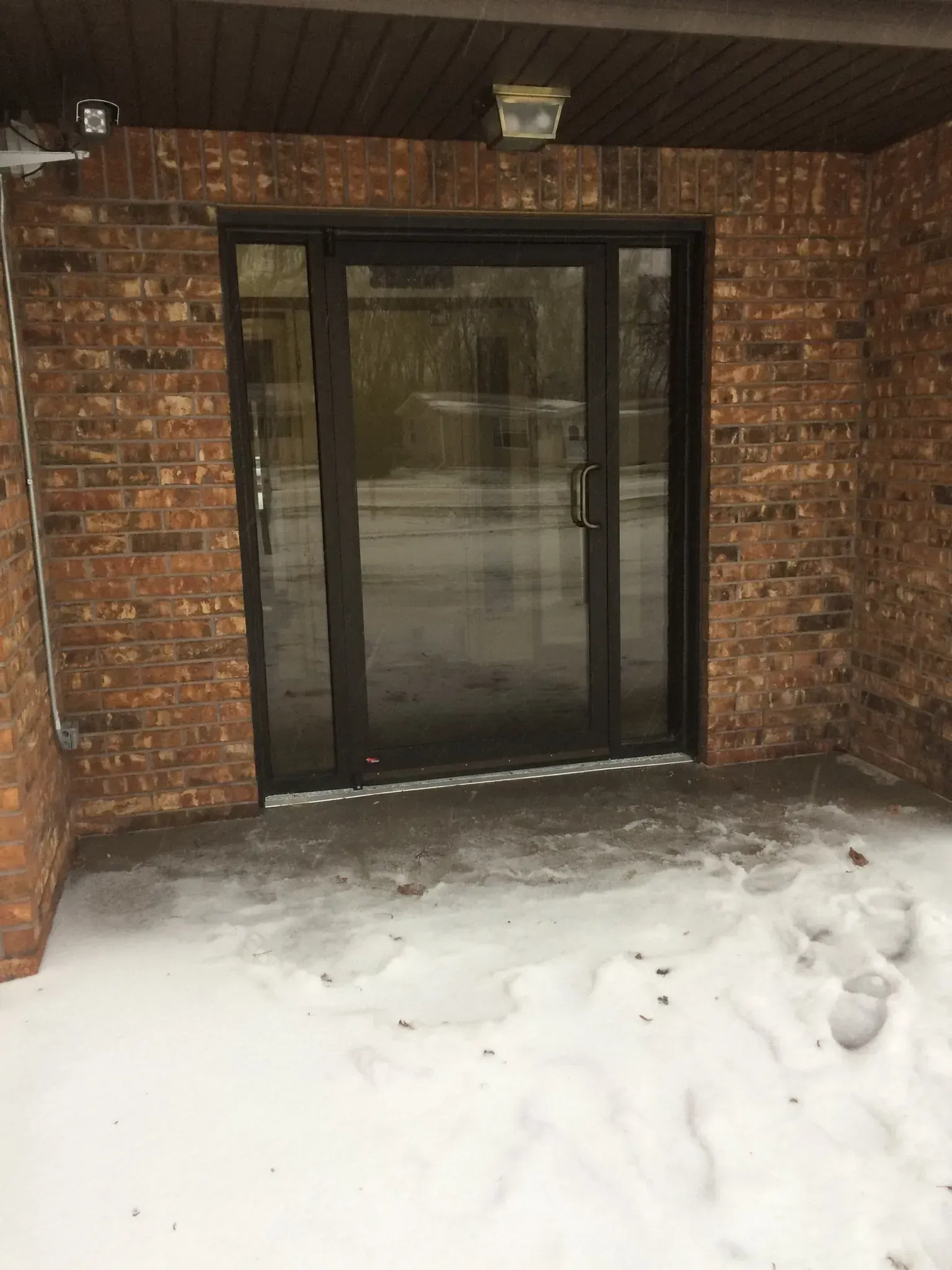 A brick building with a glass door and snow on the ground