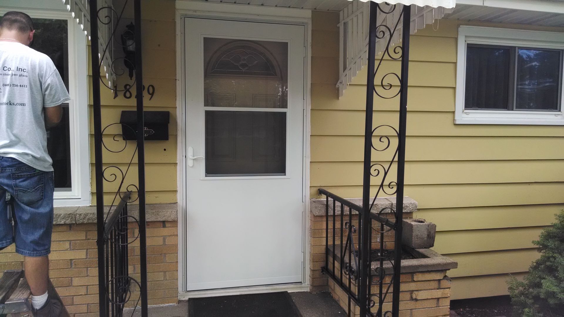 A man standing in front of a yellow house with a white door