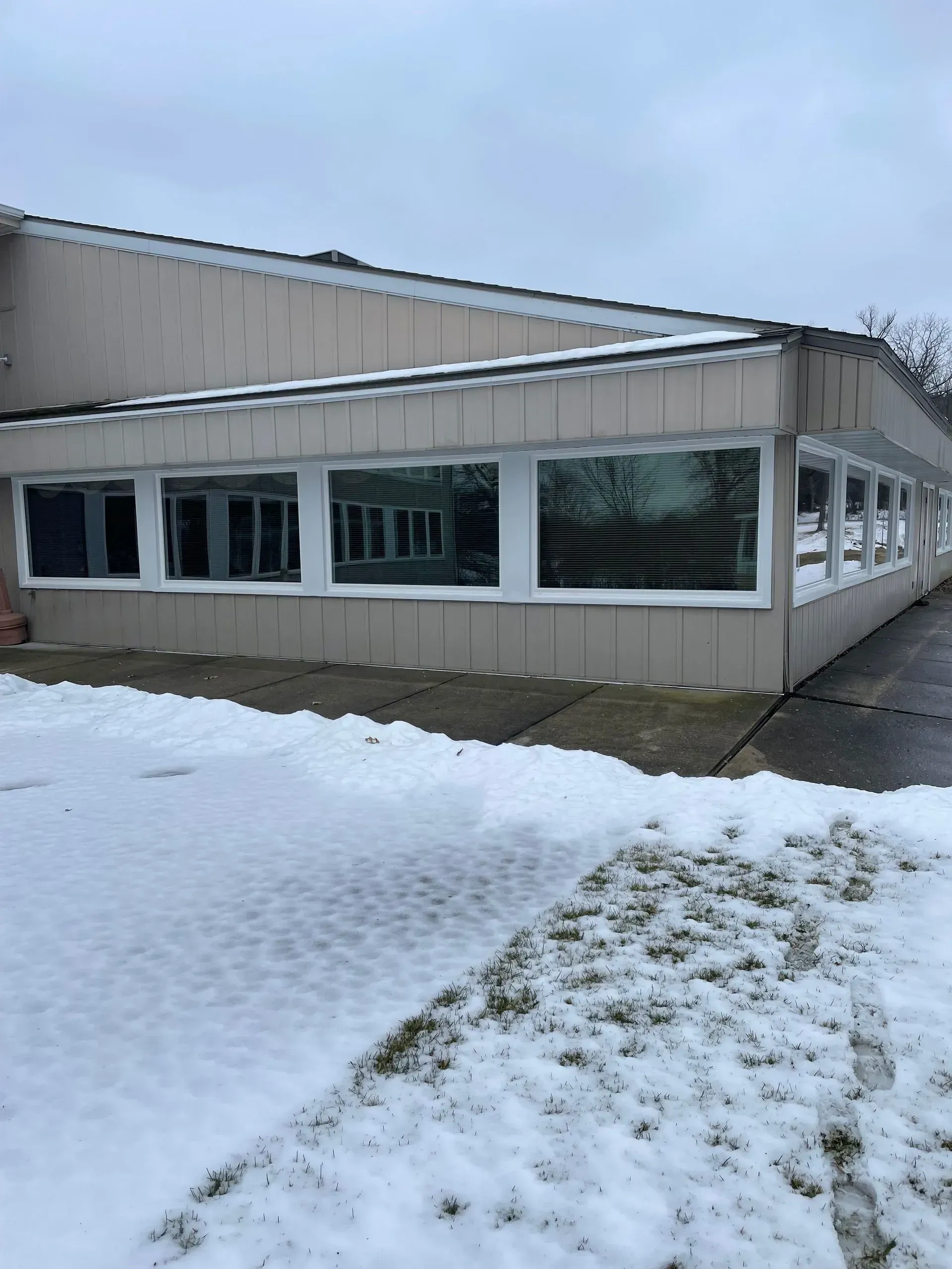 A building with a lot of windows is covered in snow.