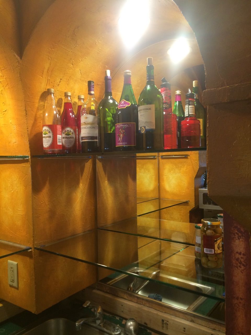 Bottles of liquor are lined up on shelves in a kitchen