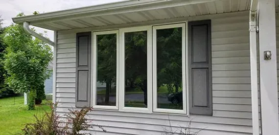A white house with a large window and shutters.