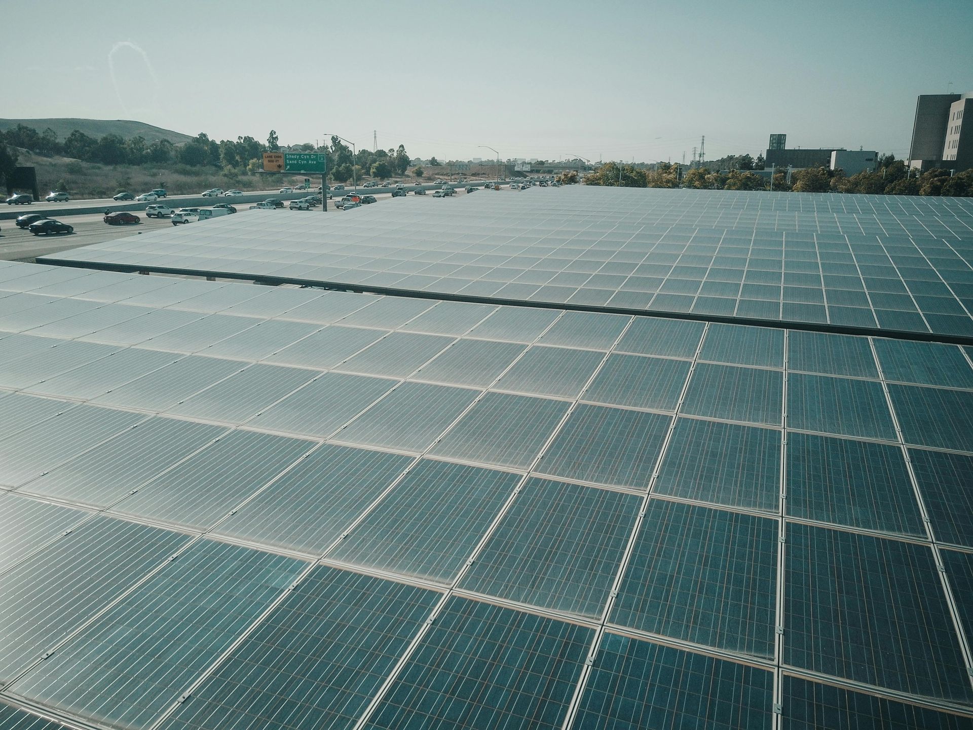A vast expanse of dark blue solar panels arranged in a grid, reflecting the bright, clear sky.