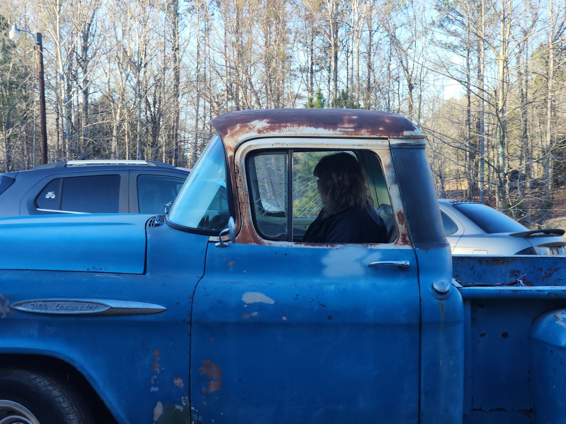 A man is sitting in the back of a blue truck