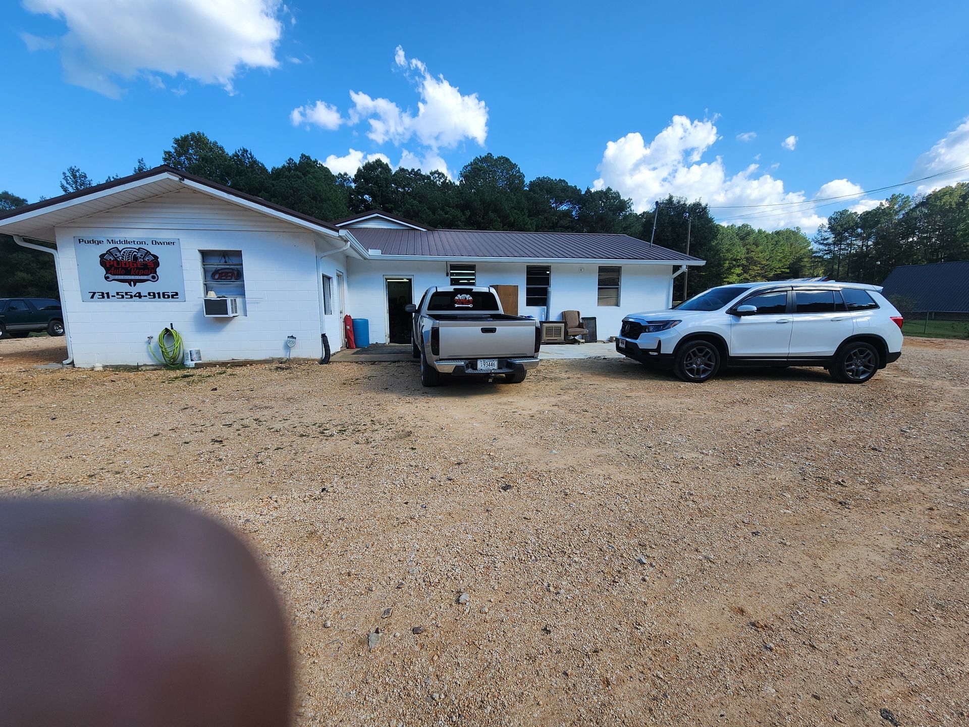 Two cars are parked in front of a white house.