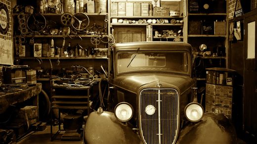 A black and white photo of an old car in a garage.