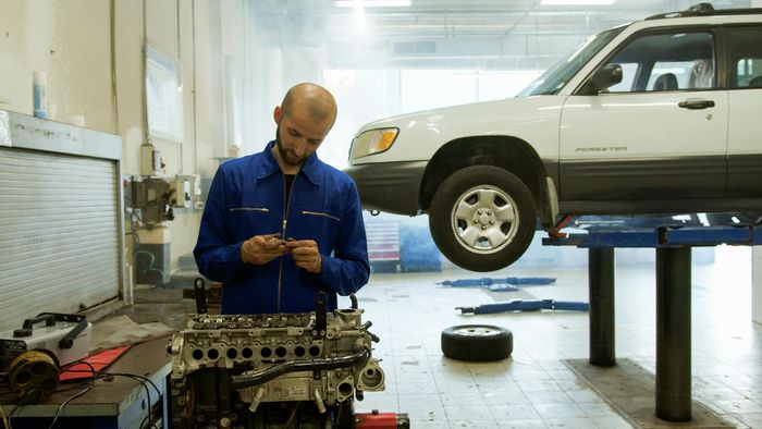A man is working on a car engine in a garage.