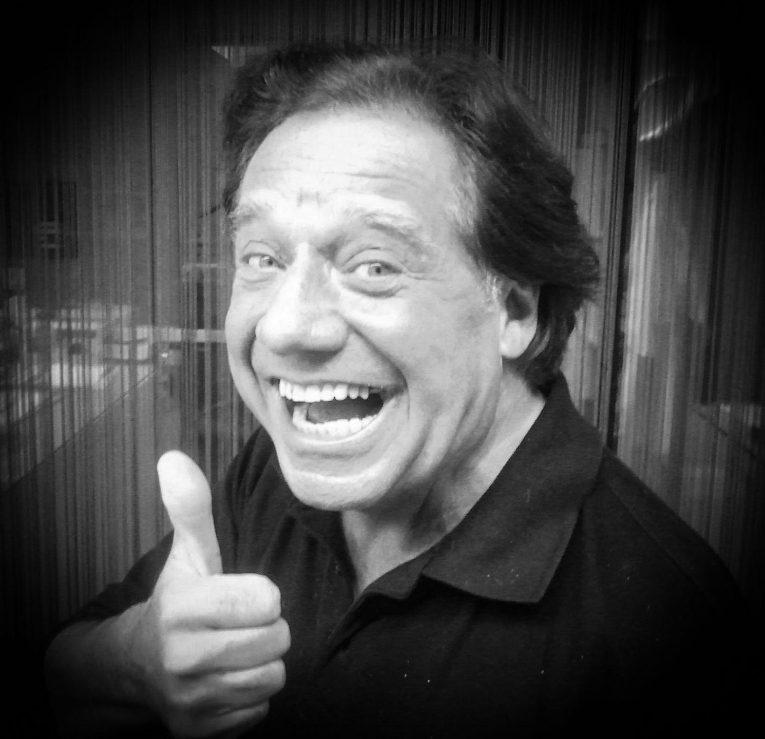 Mann lächelt und zeigt den Daumen nach oben. Schwarz-Weiß-Foto.