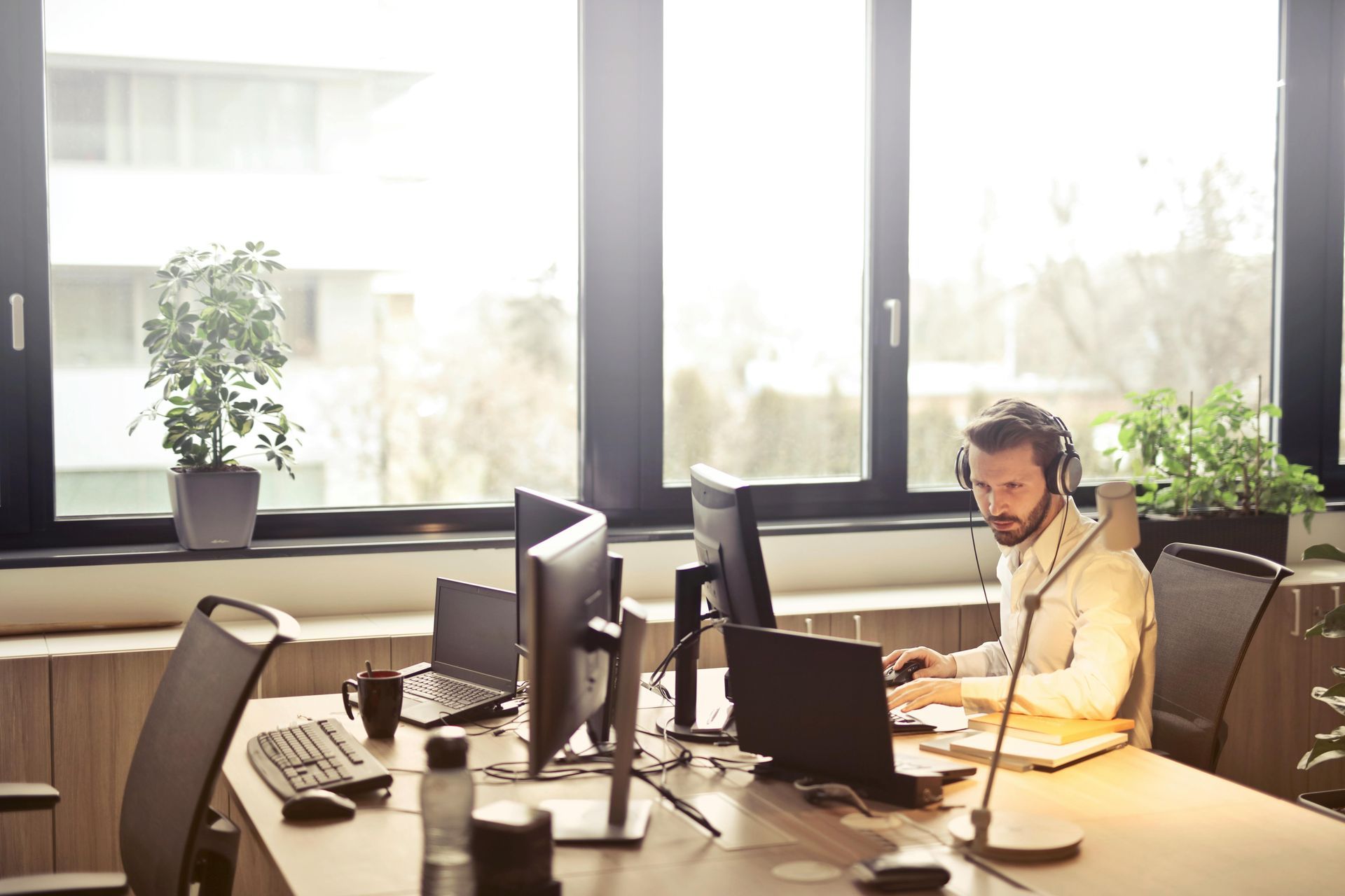 Office worker using a headset at a desk with multiple monitors in a bright office