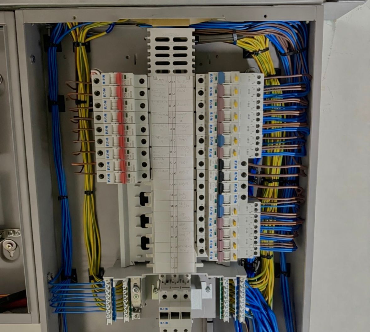 Electrical panel with colored wires and circuit breakers.