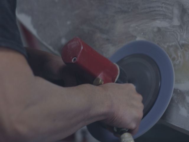Employee sanding and grinding down fiberglass