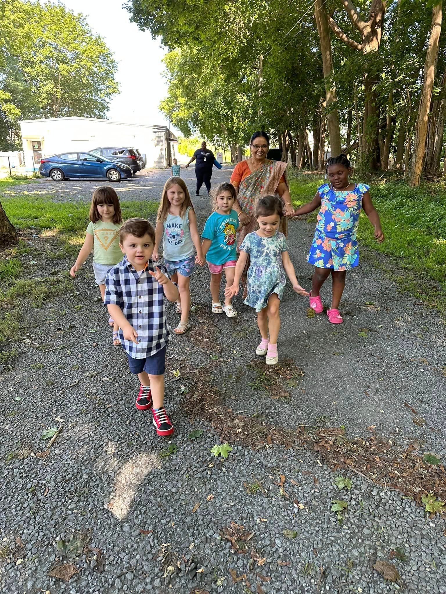 A group of children are walking down a dirt road holding hands.