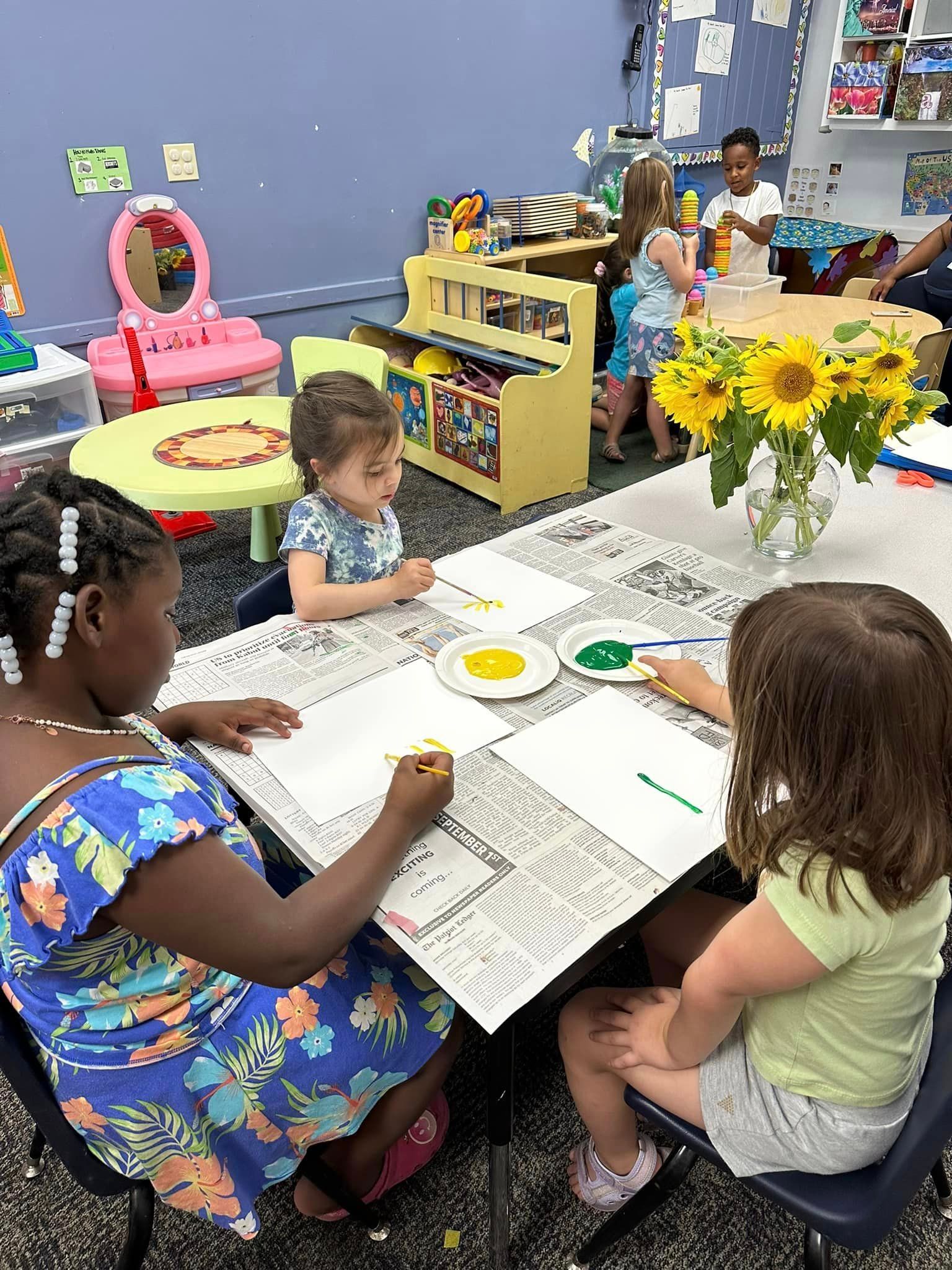 A group of young girls are sitting at a table painting.