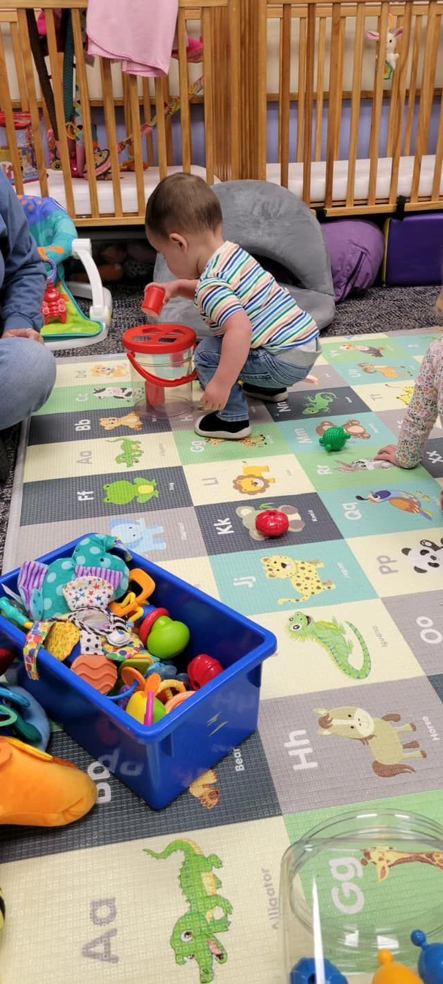 A group of children are playing with toys on a rug in a room.