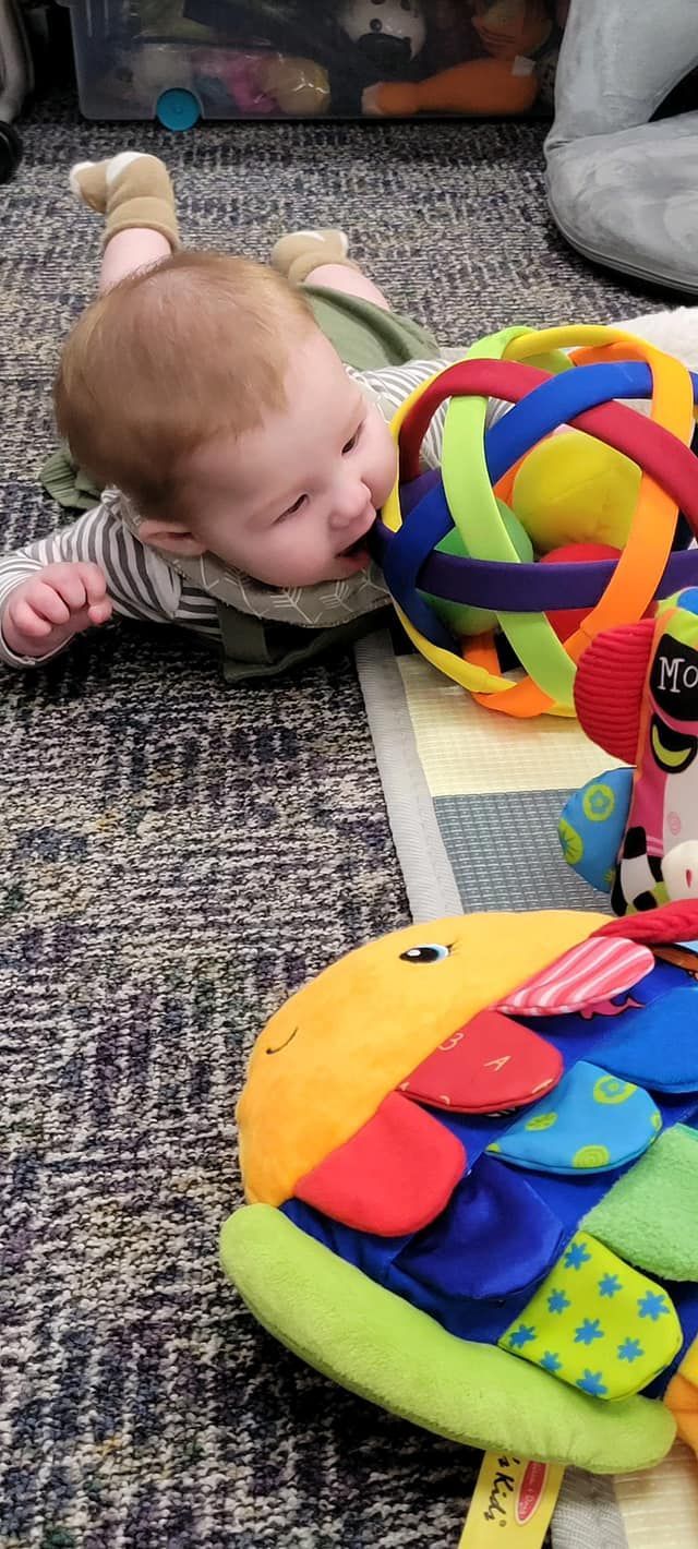 A baby is laying on the floor playing with toys.