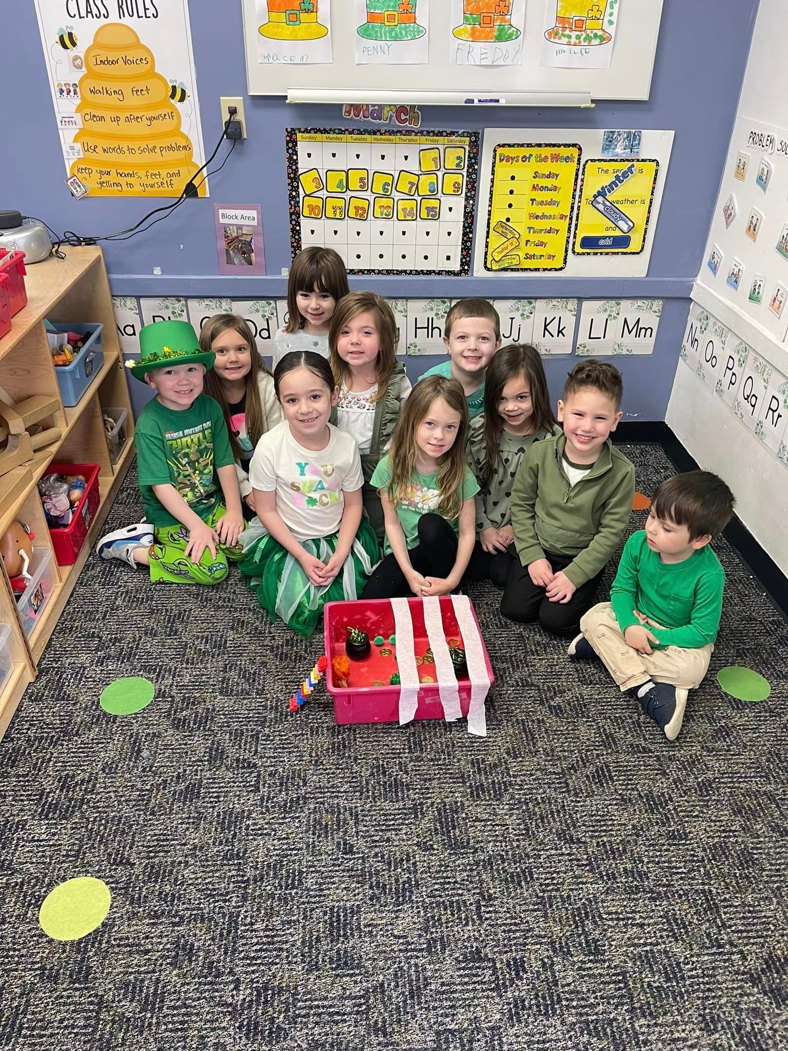 A group of children are sitting on the floor in a classroom.