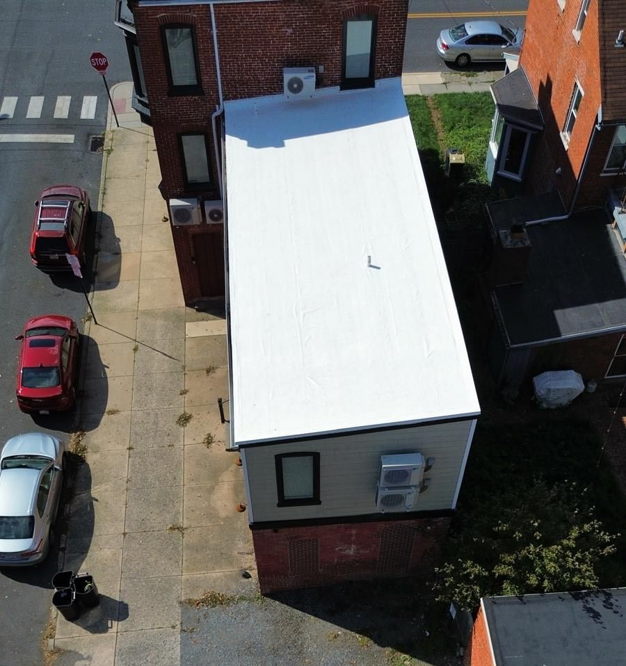 Black paint being applied to a concrete surface with a paint roller, creating a contrast.