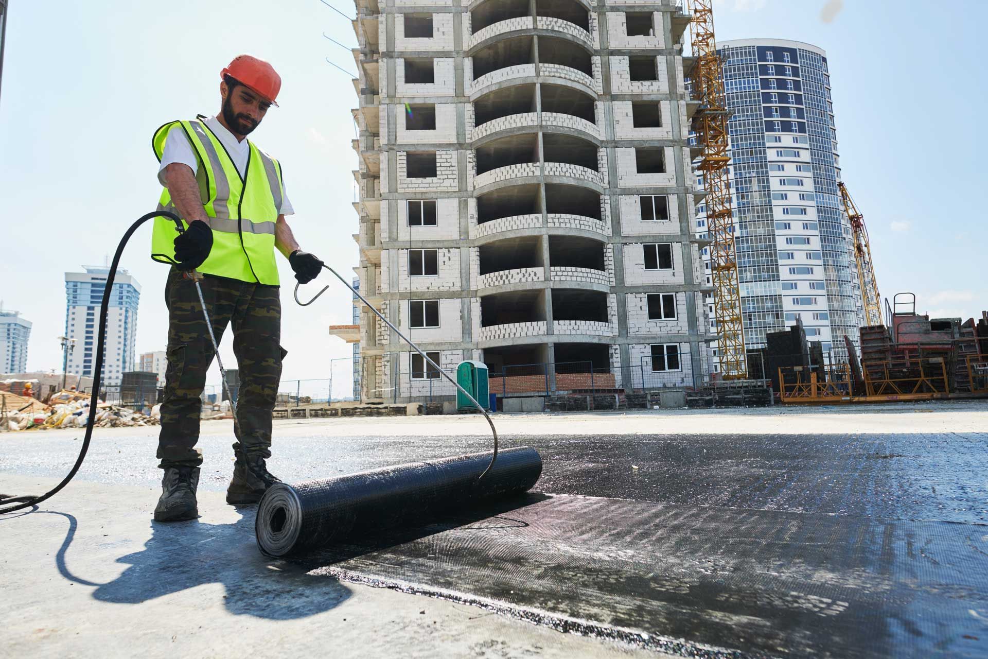 Construction worker applying sealant to a building rooftop. Construction worker applying sealant to a building rooftop.