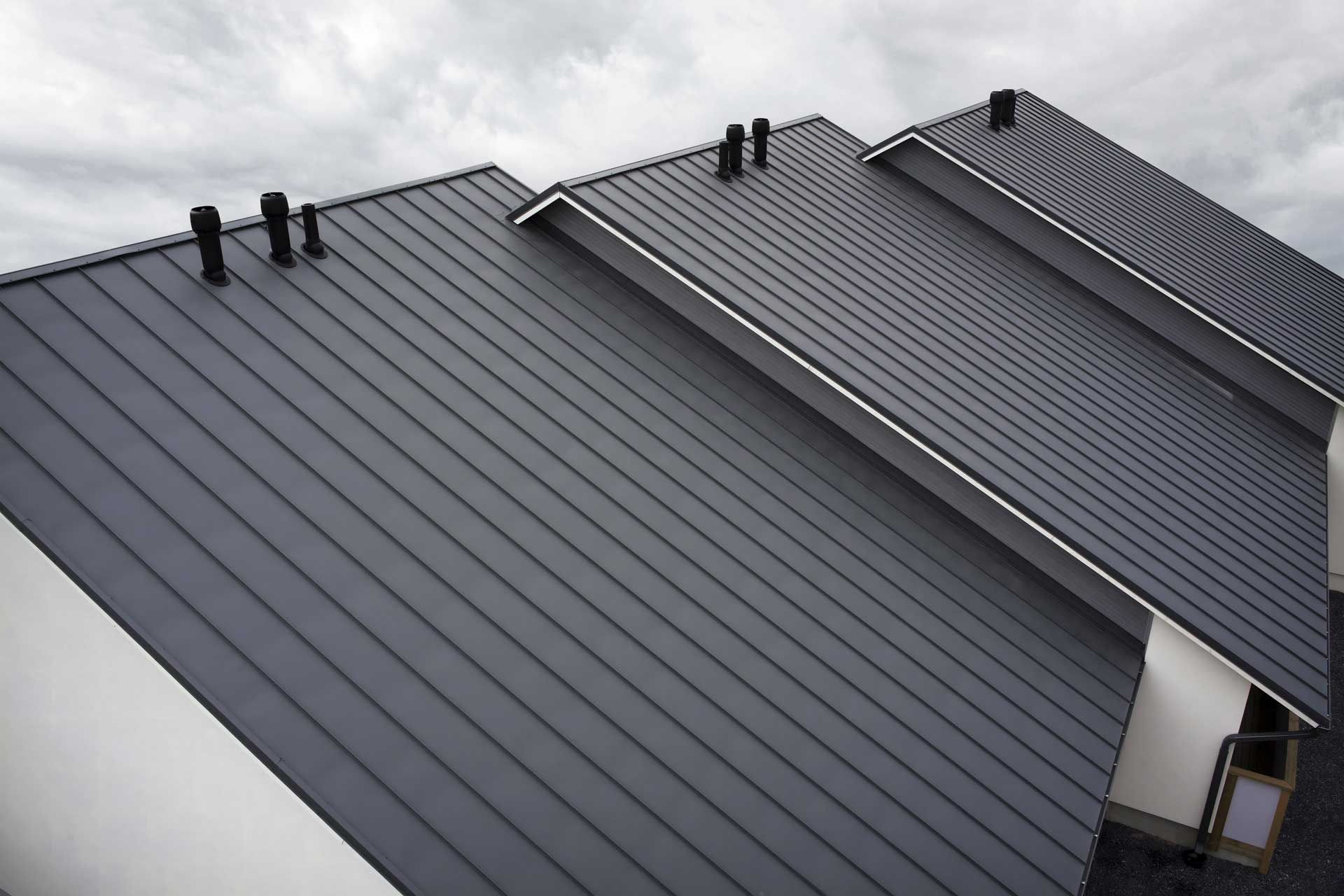Dark gray metal roof with vertical lines and black vents.