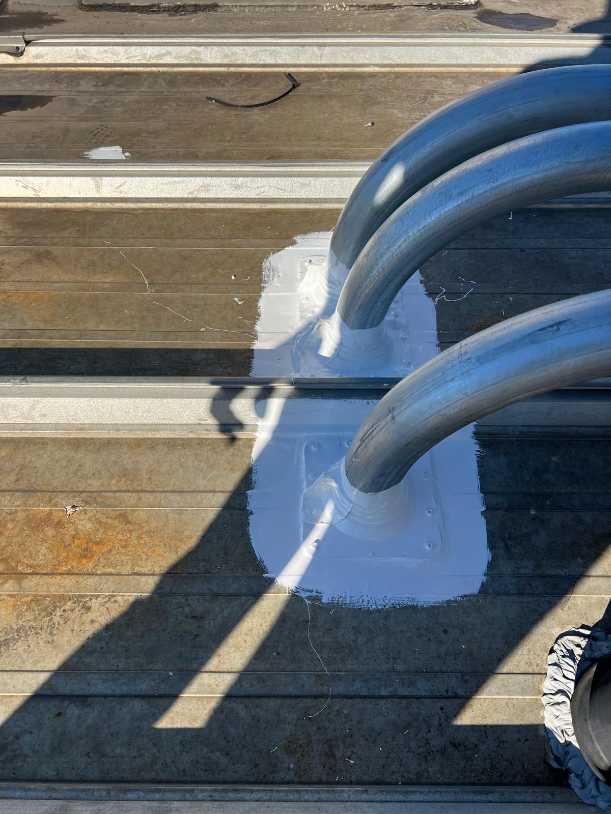 Person using a torch to apply sealant to a flat roof, near a wall.