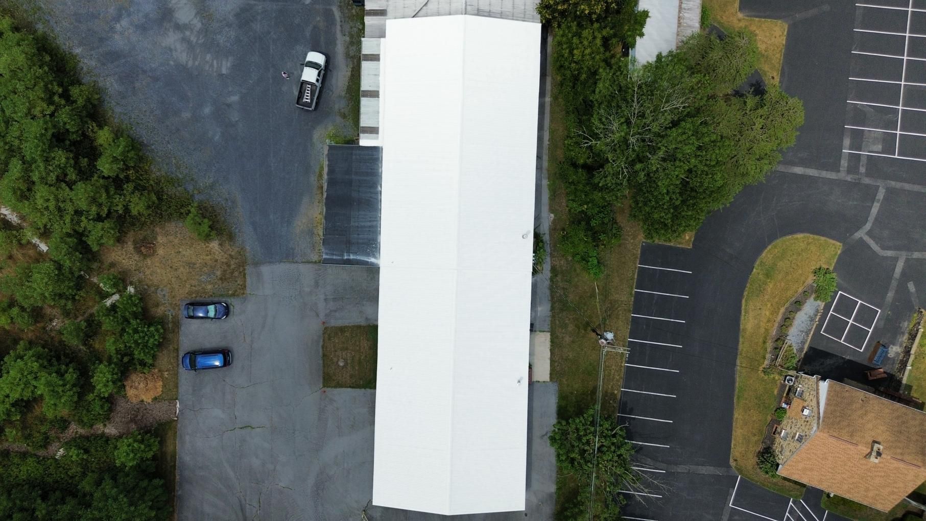 Workers applying black sealant to a concrete surface with rollers, rolling out a black membrane in an outdoor setting.