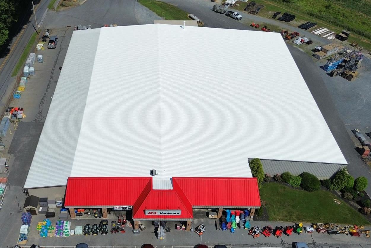 Person applying dark sealant to a roof with a roller. Person applying dark sealant to a roof with a roller.