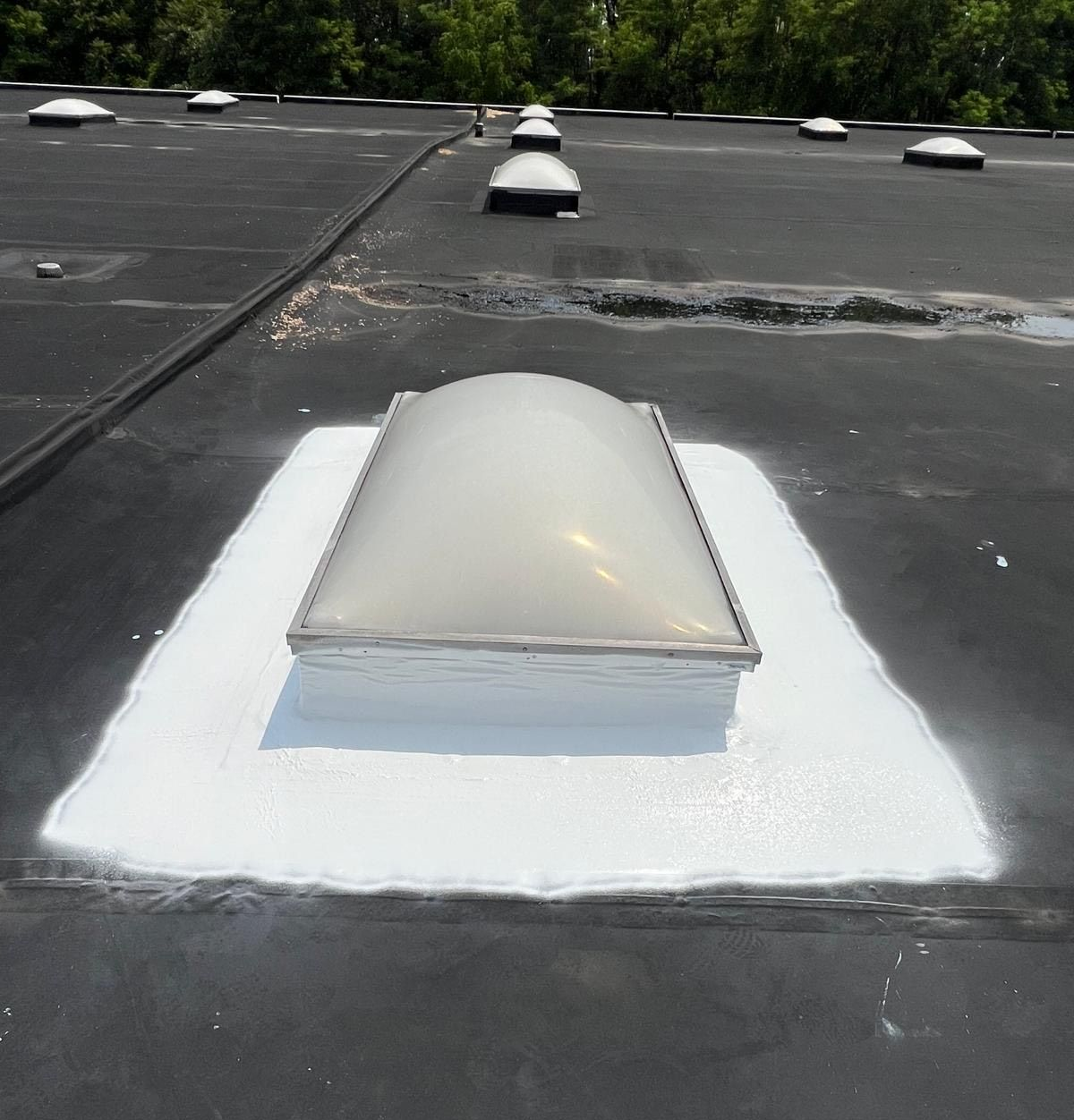 Person using a torch to install roofing material on a white surface.
