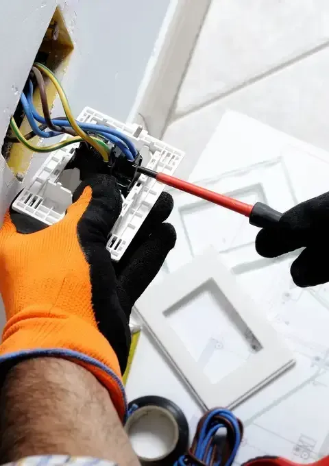 Electrician Wearing Work Gloves Using a Screwdriver — Peter Gow Electrical in Casino, NSW
