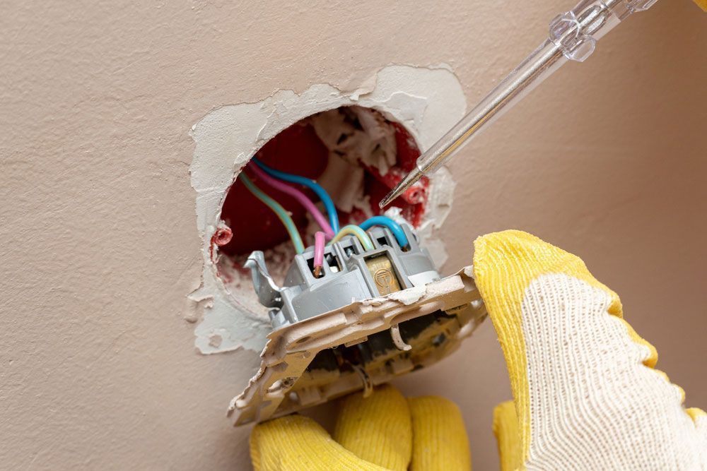 A Person Is Fixing an Electrical Outlet with A Screwdriver — Peter Gow Electrical in Lismore, NSW