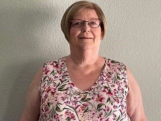 A man in a suit and tie is sitting in front of a window.