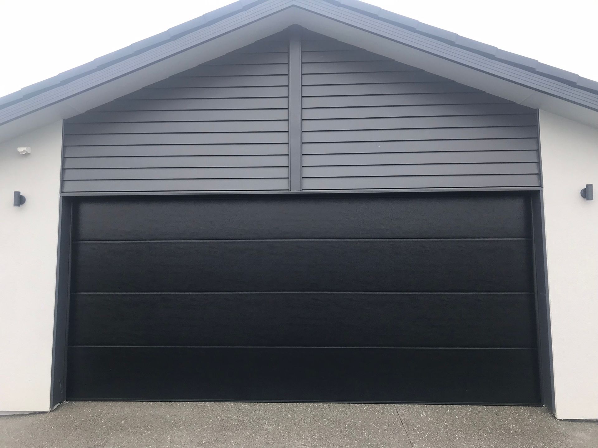 A black garage door is on the side of a house.