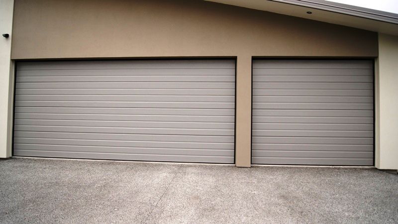 There are two garage doors on the side of a house.