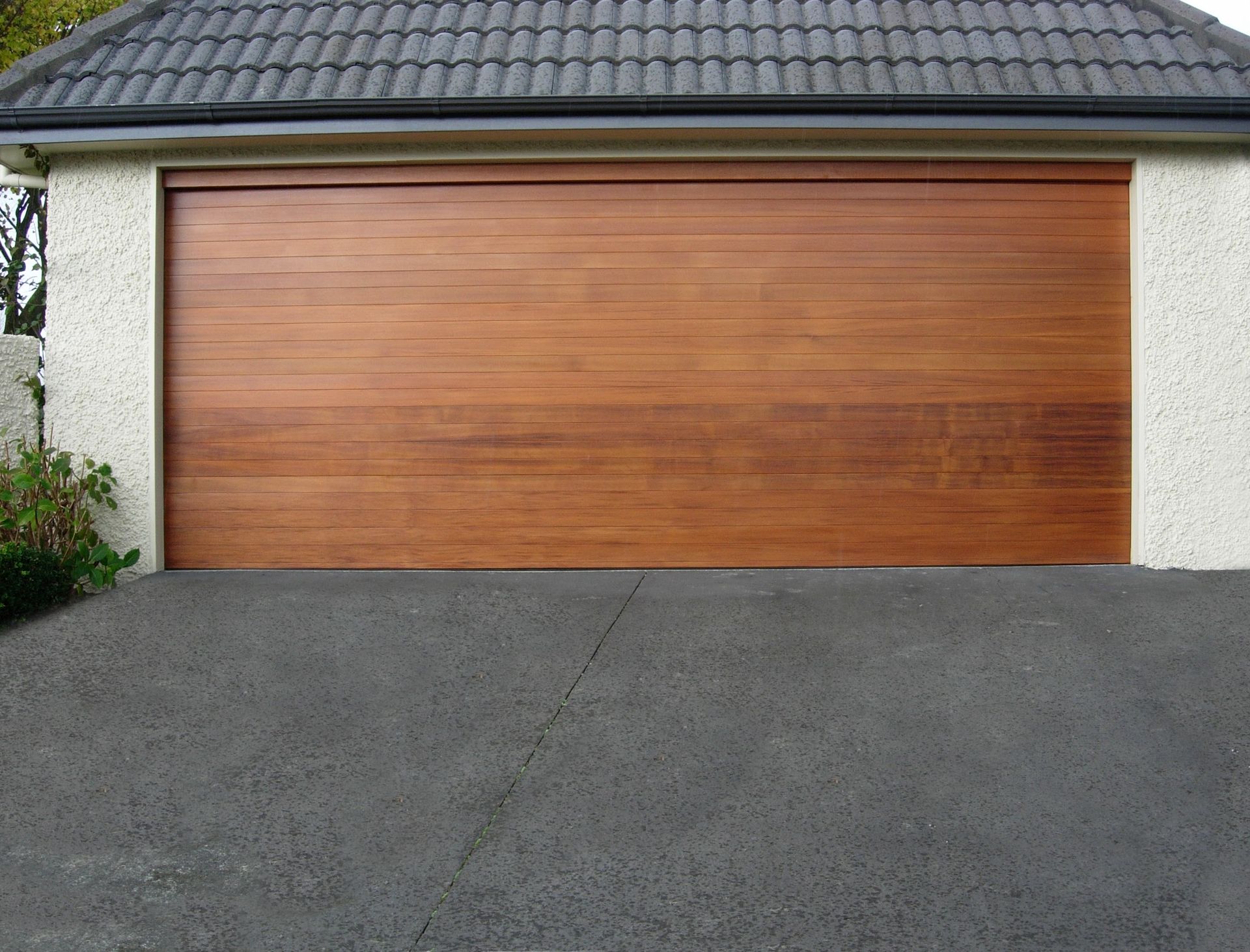 A wooden garage door is sitting in the driveway of a house.