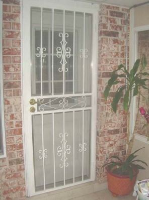 White metal security door with brick wall and potted plant beside it