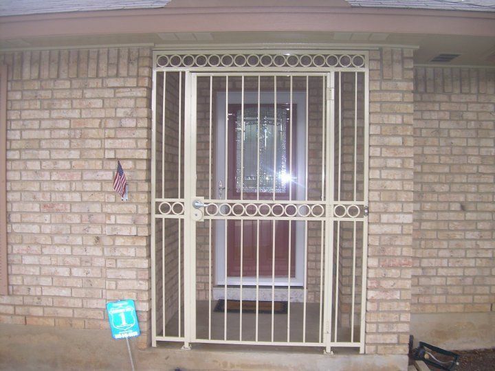 Front porch with beige brick wall and white security door over a wooden door