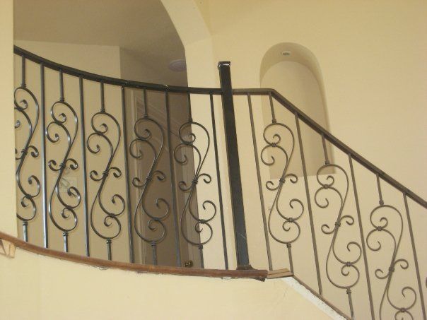Interior staircase with black wrought-iron railing and beige walls