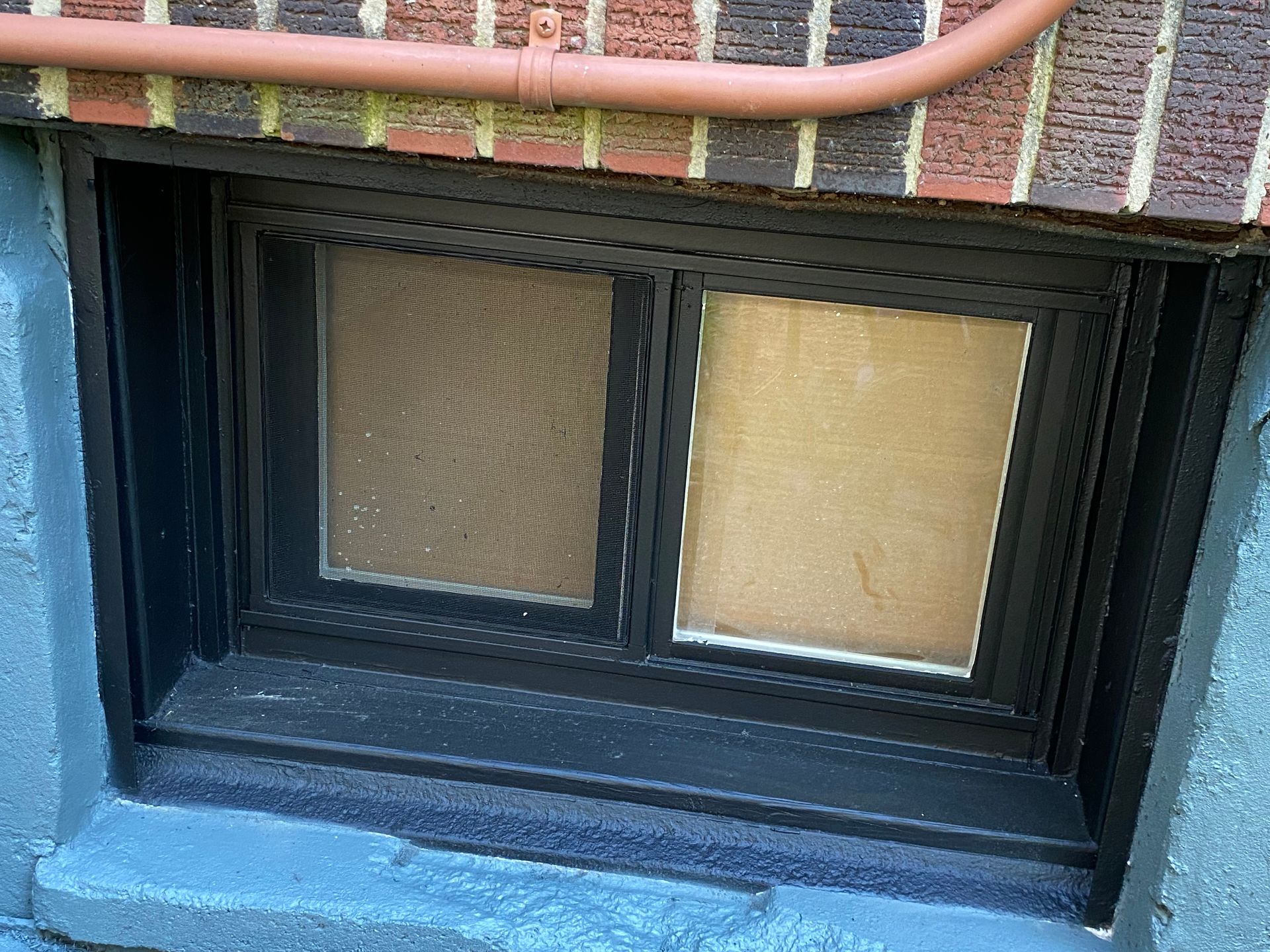 A window with a brick wall behind it