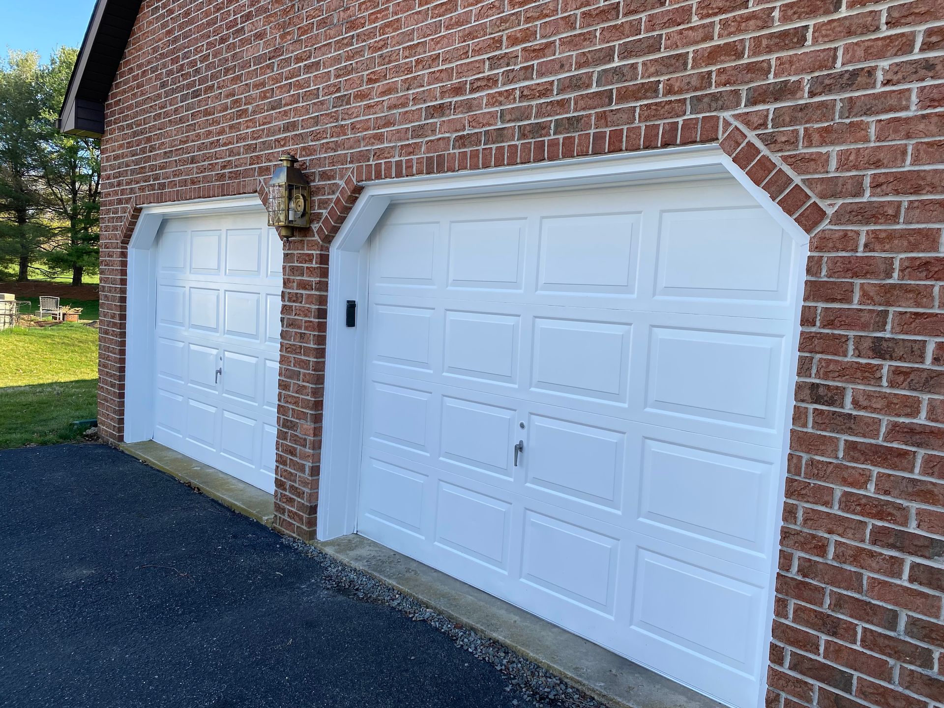 Two white garage doors on a red brick building.