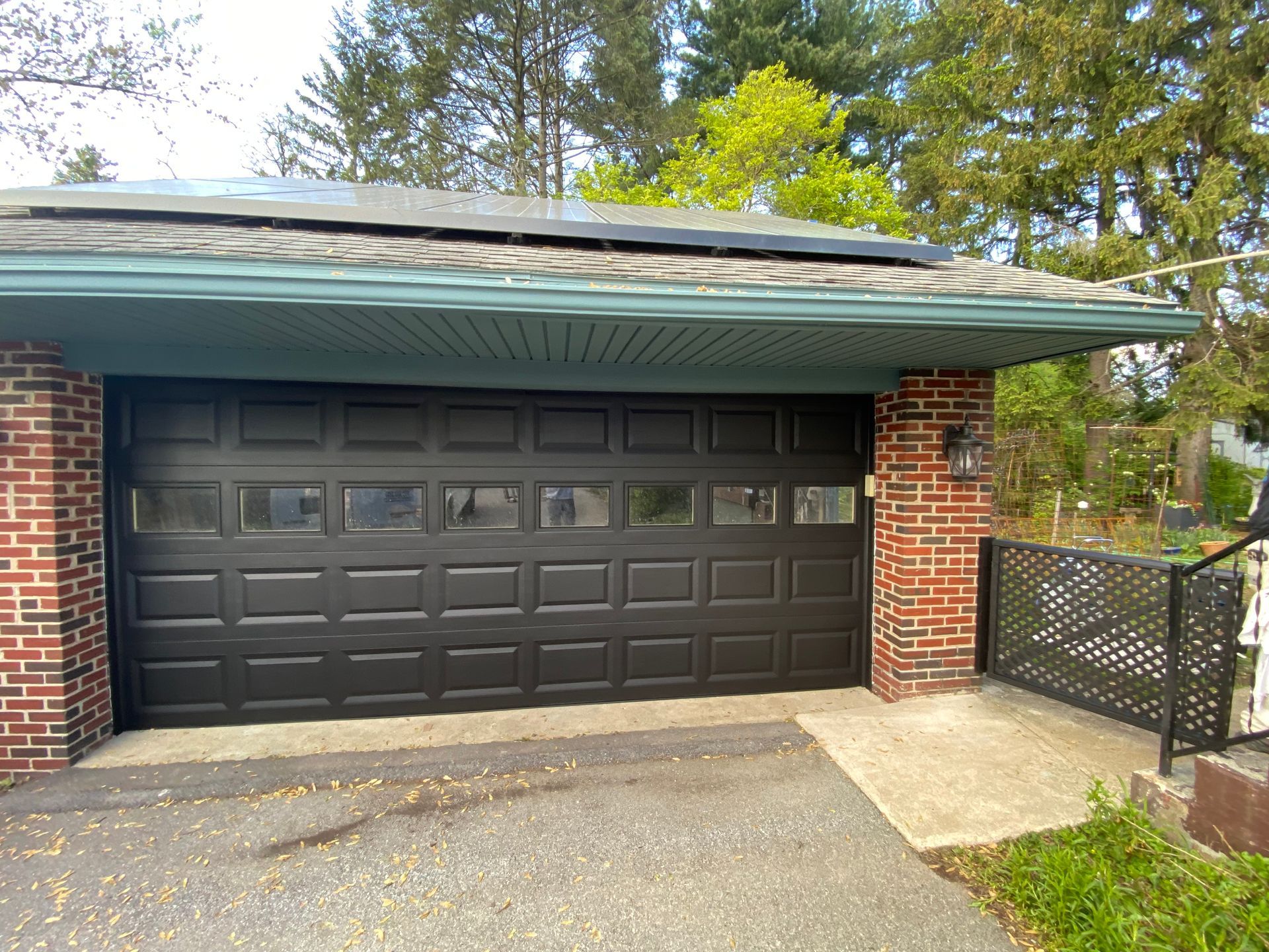 A black garage door is sitting next to a brick building.