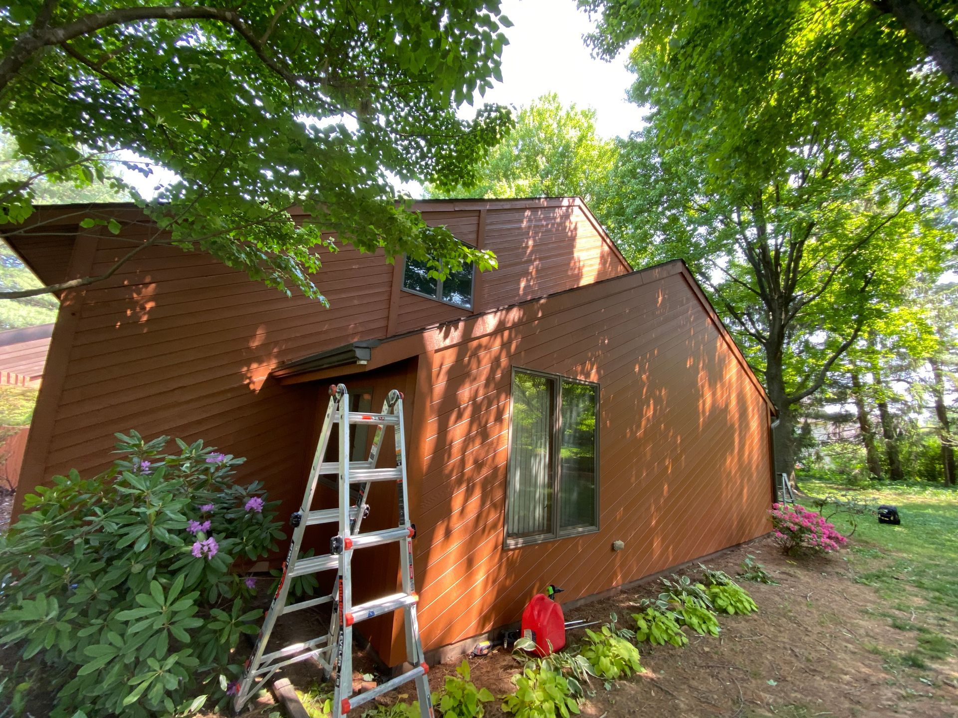 A ladder is sitting in front of a brown house.
