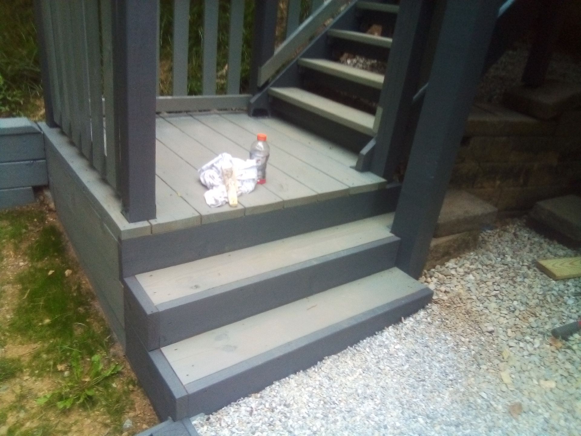 A bottle of cleaner sits on the steps of a deck